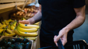 Shopper picks up Fairtrade bananas next to Fairtrade avocados