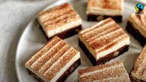 Mocha espresso brownies with coffee cream and a dusting of cocoa on a white plate