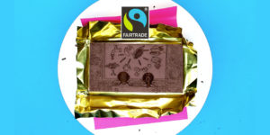 Chocolate bar carved with symbols representing Fairtrade - tap, tree, logo, corn, gender signs, plate with cutlery, money, two people sat on a bench looking at the symbols