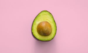 An open avacado on a pink background