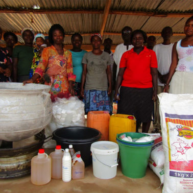 Women standing in front of soap making apparatus