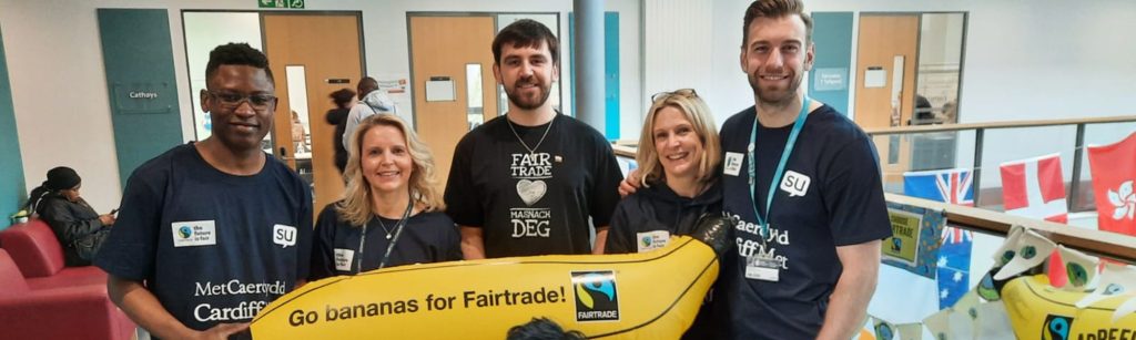 students from Cardiff Met holding an inflatable banana with 'go bananas for Fairtrade!' written across it.